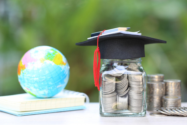 Graduation hat on the glass bottle and books on natural green background, Saving money