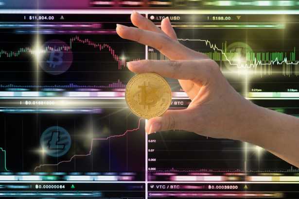 Closeup hand holding bitcoin over the Cryptocurrency trading scr