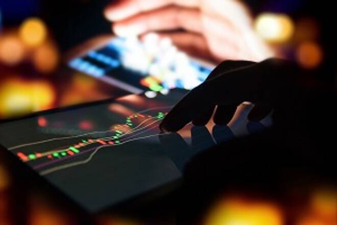 Silhouette finger on tablet with graph stock market trading screen with abstract blur smartphone bokeh background , stock market concept