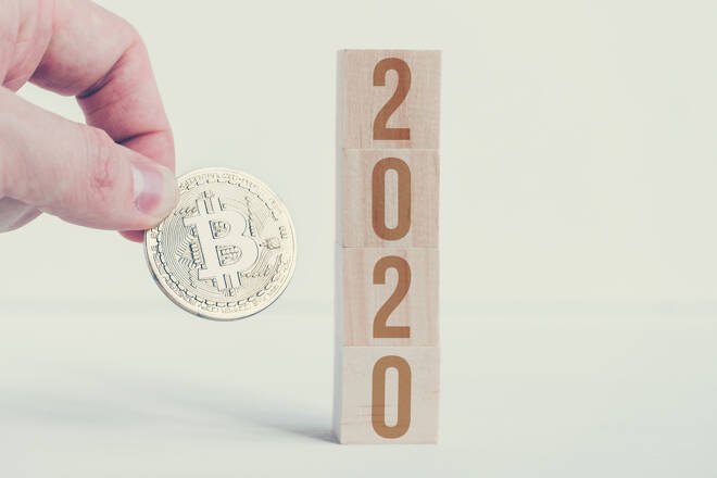 Bitcoin hold hand with numbers 2020 on wooden cubes o with a white background. The success of changes cryptocurrency in the new year. Close up. Toned