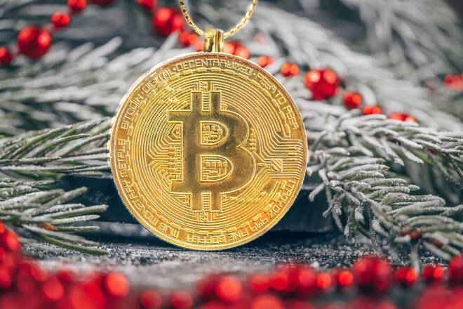 Gold bitcoin hanging on a snowy branch of a Christmas tree with red beads close-up. Beautiful Christmas, new year background with bitcoin
