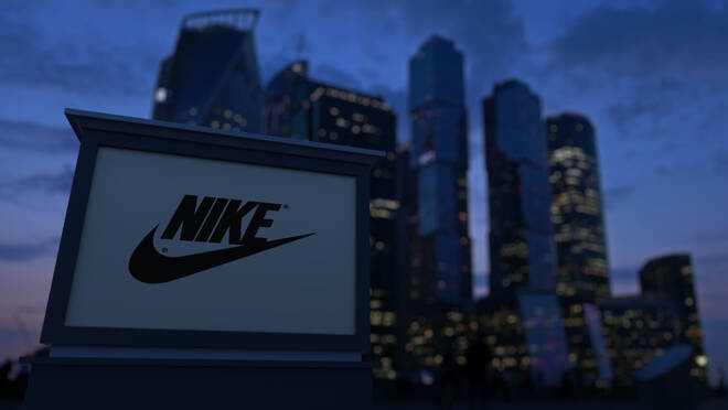 Street signage board with Nike inscription and logo in the evening. Blurred business district skyscrapers background. Editorial 3D United States