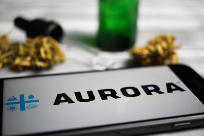 Closeup of mobile phone screen with logo lettering of cannabinoid company aurora cannabis, blurred marijuana and pipette background