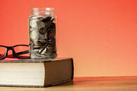 EDUCATION FUND CONCEPT with coins in a glass jar and old book.