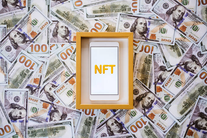 Non-fungible token NFT, crypto art, digital art, new type of cryptorurrency. Cell phone with golden NFT text in golden frame as art object on dollars fxempire