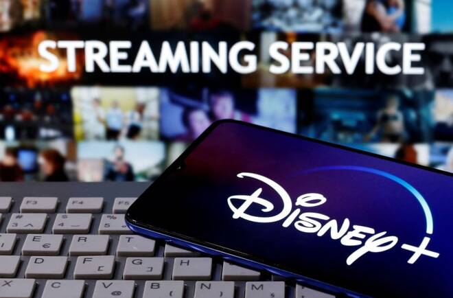 Smartphone with the "Disney" logo is seen on a keyboard in front of the words "Streaming service