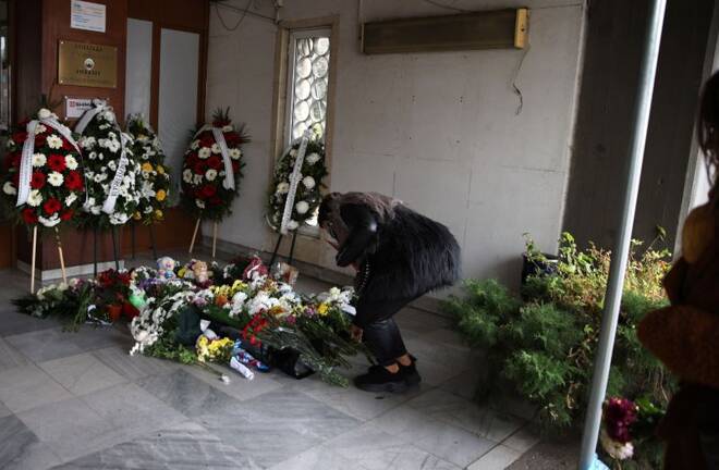 Woman lays flowers at a makeshift memorial for the victims of a bus accident, in Sofia