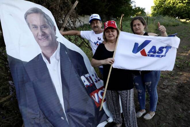Farmer Luis Jara and his family pose for a picture next to a banner of Chilean presidential candidate Jose Antonio Kast in Yumbel