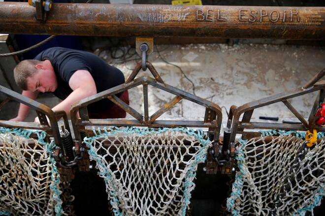 A French fisherman prepares drag nets on the French trawler Bel Espoir before it leaves the harbour of Port-en-Bessin on the eve of the start of the scallop fishing season