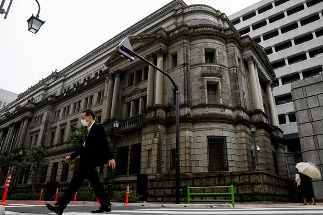 A man wearing a protective mask walks past the headquarters of the Bank of Japan in Tokyo