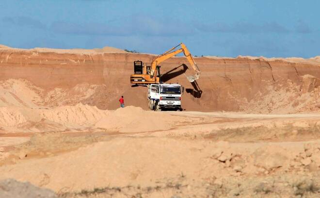 A excavator dumps bauxite ore into a dump truck at a mine belonging to China's Bosai Minerals Group in Linden