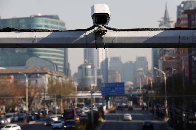 A security surveillance camera overlooks a street as cars drive by in Beijing