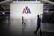 People walk past an American Airlines logo at John F. Kennedy (JFK) airport in in New York