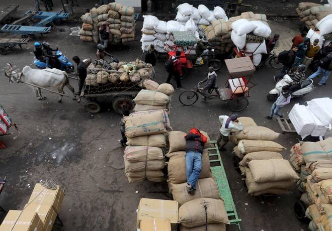 A labourer sleeps on sacks as traffic moves past him in a wholesale market in the old quarters of Delhi