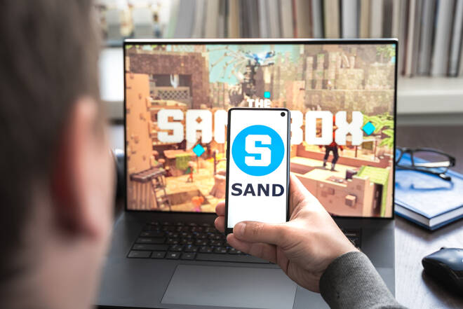 Russia Moscow 30.05.2021.Logo,screenshot of blockchain nft ethereum cryptocurrency game Sandbox in laptop,mobile phone.Man playing with crypto coins,token sand.Earning digital money.Lands,heroes