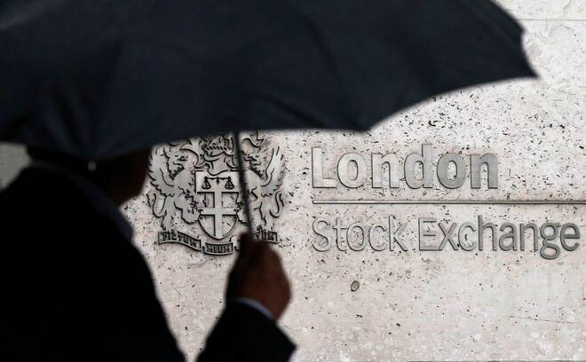 omeA man shelters under an umbrella as he walks past the London Stock Exchange
