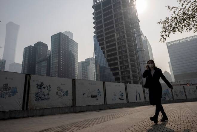 A woman walks in the Central Business District (CBD) on a hazy morning in Beijing