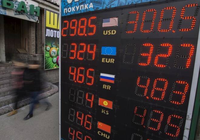 A couple walks past a board showing currency exchange rates in Almaty, Kazakhstan