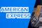 Credit card is seen in front of displayed American Express logo in this illustration