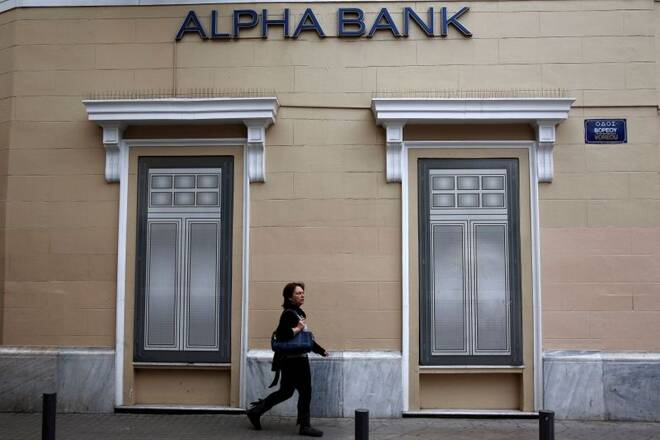 A woman makes her way past the logo of Alpha Bank in Athens