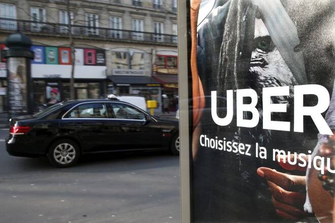File photo shows a taxi passing by an advertisement for the Uber car and ride-sharing service displayed on a bus stop in Paris