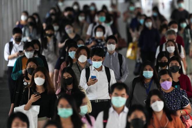 People wearing face masks as a measure to prevent the spread of COVID-19 are seen at a train station in Bangkok