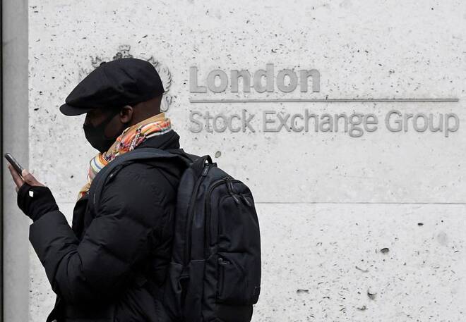 A man wearing a protective face mask walks past the London Stock Exchange Group building in the City of London financial district, whilst British stocks tumble as investors fear that the coronavirus outbreak could stall the global economy, in L