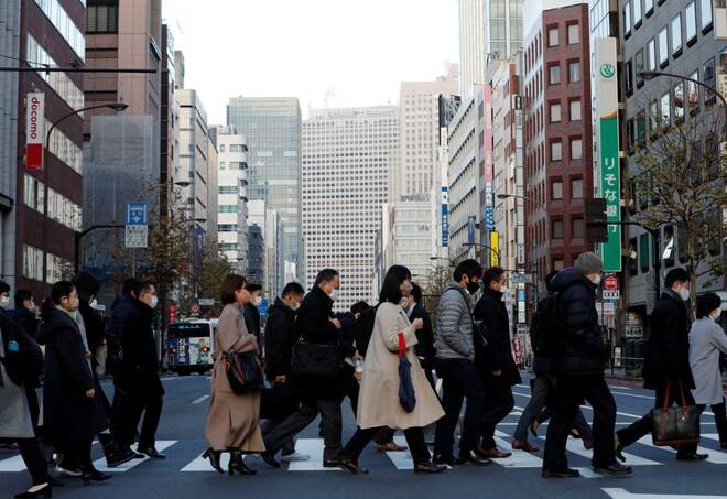 Pedestrians wearing protective masks, following the coronavirus disease (COVID-19) outbreak, make their way during commuting hour at a business district in Tokyo