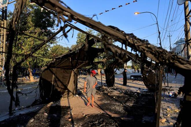 Supporter of Iraqi Shiite armed groups looks at the remains of a tent, which was burnt last night after clashes with Iraqi security forces during a protest against the election results in Baghdad