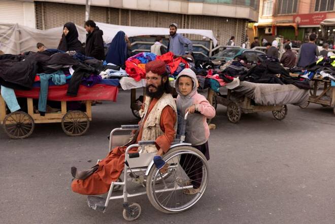A boy pushes a man's wheelchair on a street in Kabul