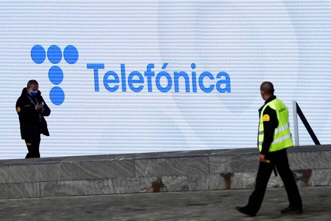 Security guards walk past a screen displaying the logo of Spanish Telecom company Telefonica in Madrid