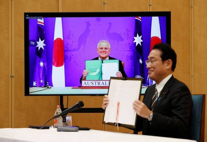 Japan's Prime Minister Fumio Kishida and Australia's Prime Minister Scott Morrison show off signed documents during their video signing ceremony of the bilateral reciprocal access agreement in Tokyo