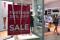 A shopper walks out of a retail store displaying a sales sign in the window at a shopping center in Sydney, Australia