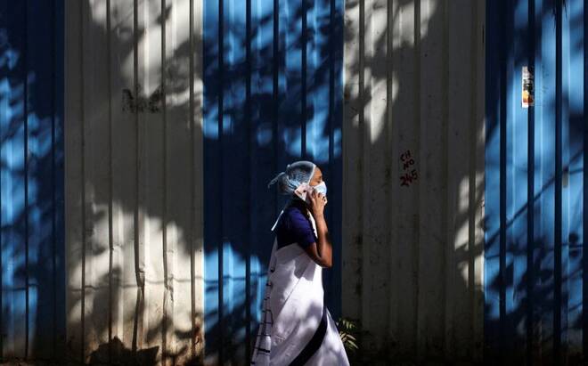 A woman wearing a protective face mask walks on a street, amidst the spread of COVID-19, in Mumbai