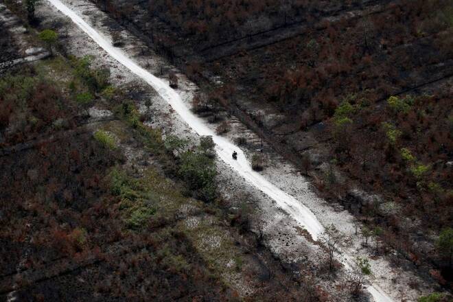 Motorcyclist drives on road through land destroyed by forest fires in Indonesia