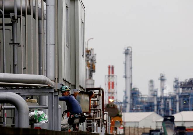 A worker is seen in front of facilities and chimneys of factories at the Keihin Industrial Zone in Kawasaki
