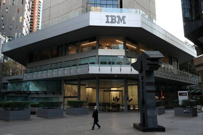 A man wearing a protective mask walks past an office building with IBM logo in Sydney