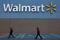 Men walk past the logo of Walmart outside a store in Monterrey