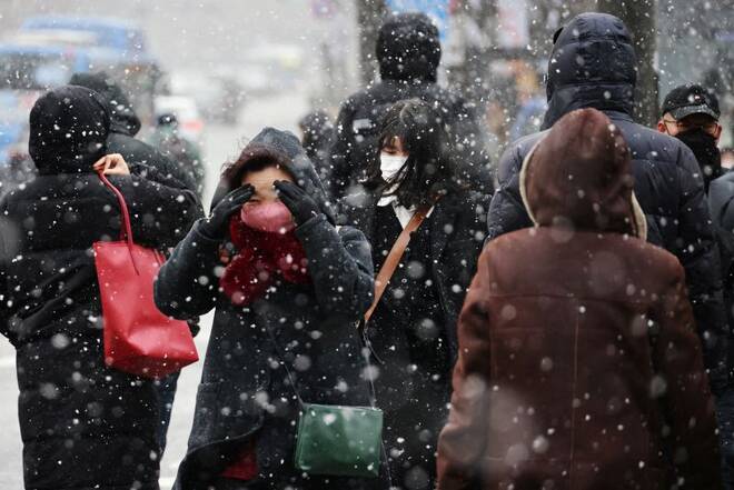 Commuters walk on a zebra crossing during snowfall, amid the coronavirus disease (COVID-19) pandemic, in central Seoul