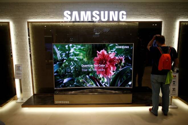 A man stands next to a Samsung Electronics "Quantum Dot" SUHD television at its headquarters in Seoul