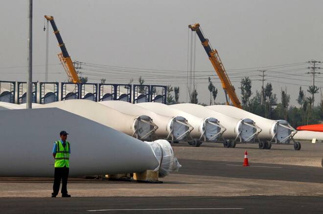 A security guard stands next to blades and bases for wind turbines in the grounds of the Vestas Wind Technology company's factory in Tianjin, China