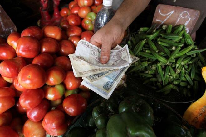 A man shows Cuban Peso bills at a farmers' market in Havana