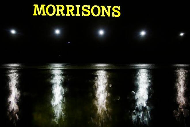 The illuminated logo shines above the wet car park of a Morrisons supermarket store in Croydon