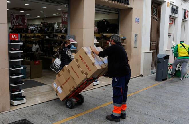 A worker pushes a cart with boxes into a shoe shop in Ronda