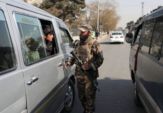 A Taliban fighter searches a car as he guards a checkpoint in Kabul, Afghanistan