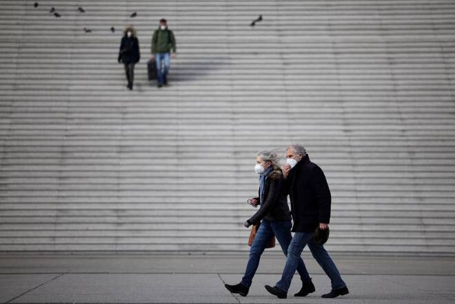 People wearing protective face masks walk past the steps near the Grande Arche in La Defense