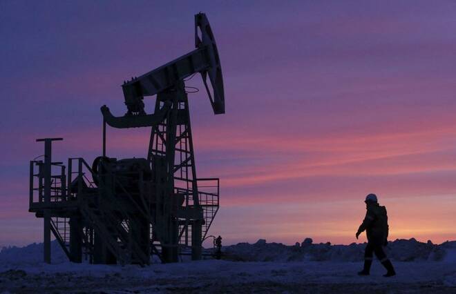 A worker walking past a pump jack on an oil field owned by Bashneft company near Nikolo-Berezovka