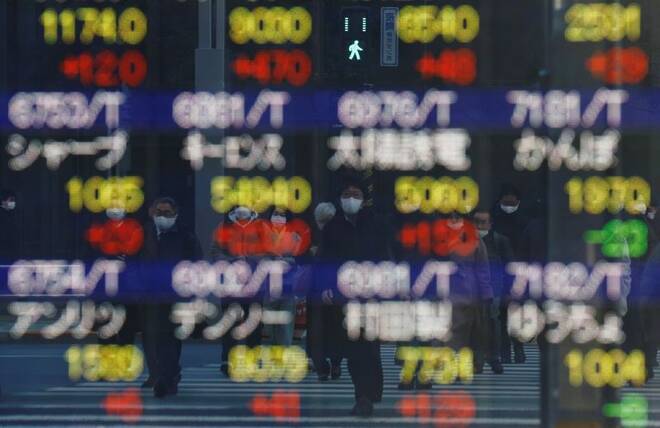 Pedestrians wearing protective masks, amid the coronavirus disease (COVID-19) outbreak, are reflected on an electronic board outside a brokerage in Tokyo