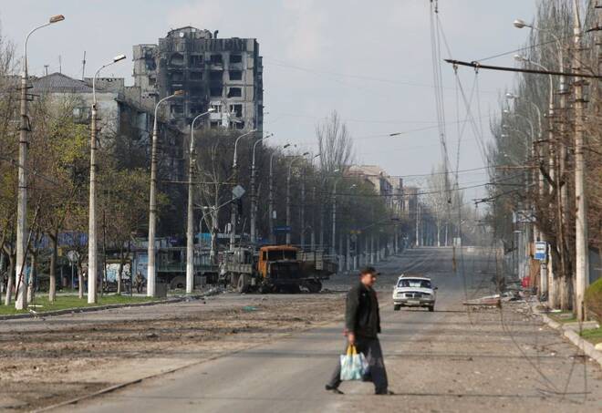 A local resident crosses a damaged street in Mariupol