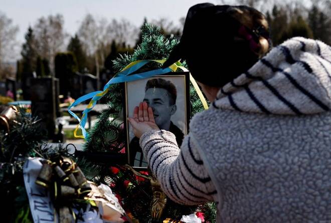 Natalia Evdokimova, 46, touches a photograph of her son Dmytro Evdokimov, 23, who was killed in a battlefield near Izium in Kharkiv region, as she mourns him beside his grave at the cemetery in Trostianets, Sumy region